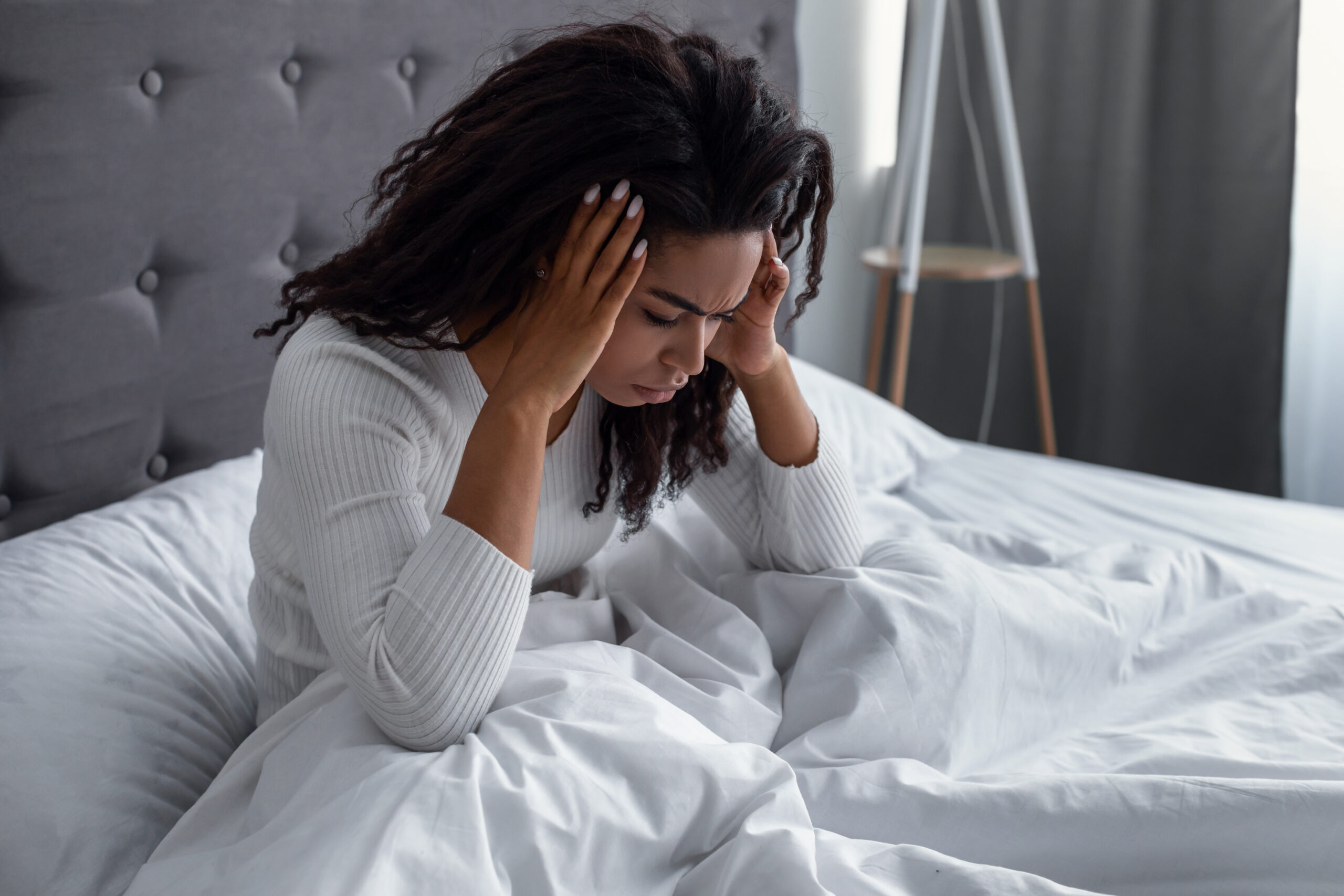 Black woman suffering from headache or migraine in bed Tips for dealing with the 8 most usual migraine causes