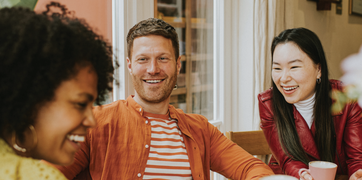 Three people sitting around each other smiling